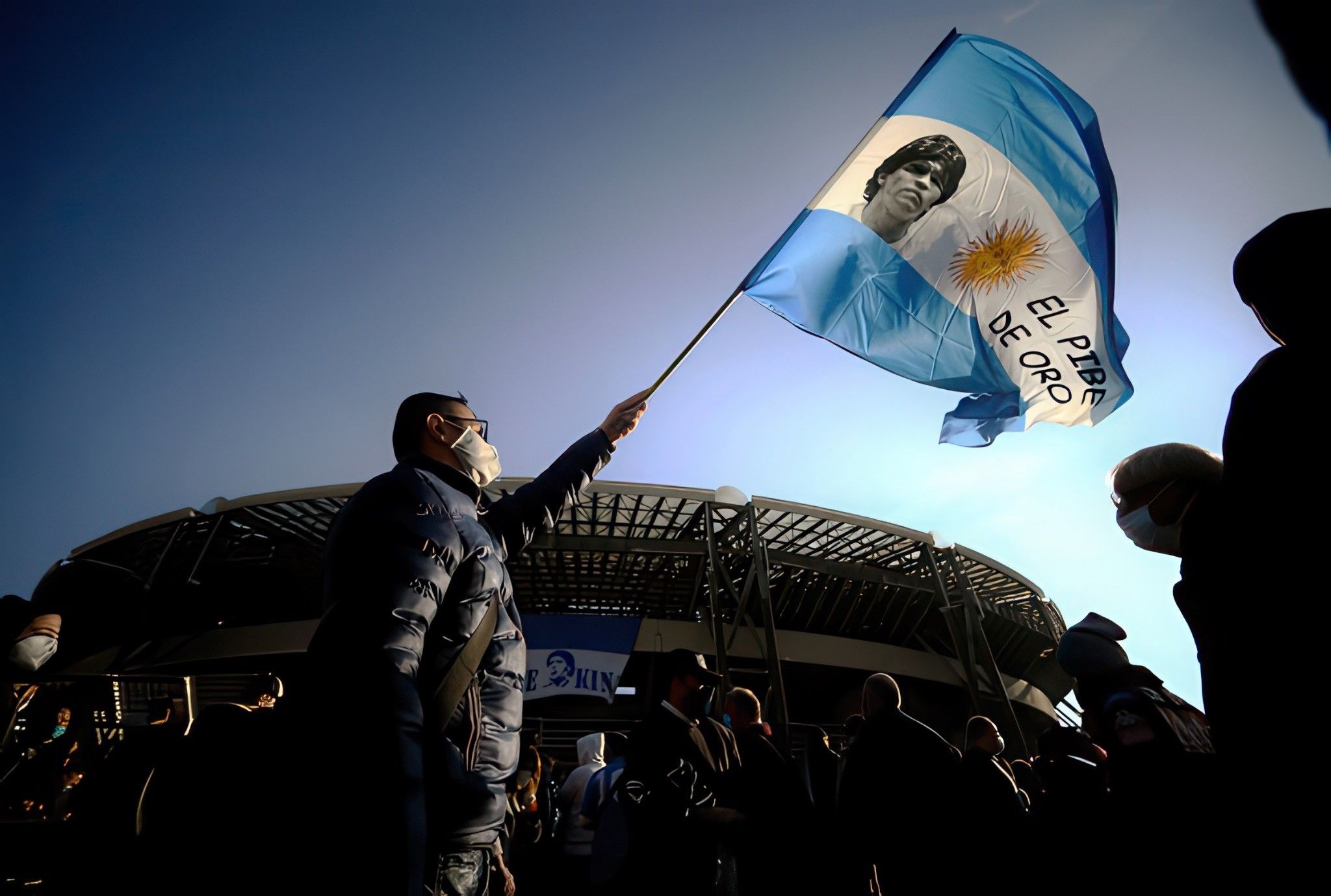 After Maradona’s death, an Italian fan holds a flag with his image. Credit: FILIPPO MONTEFORTE/AFP via Getty Images. 